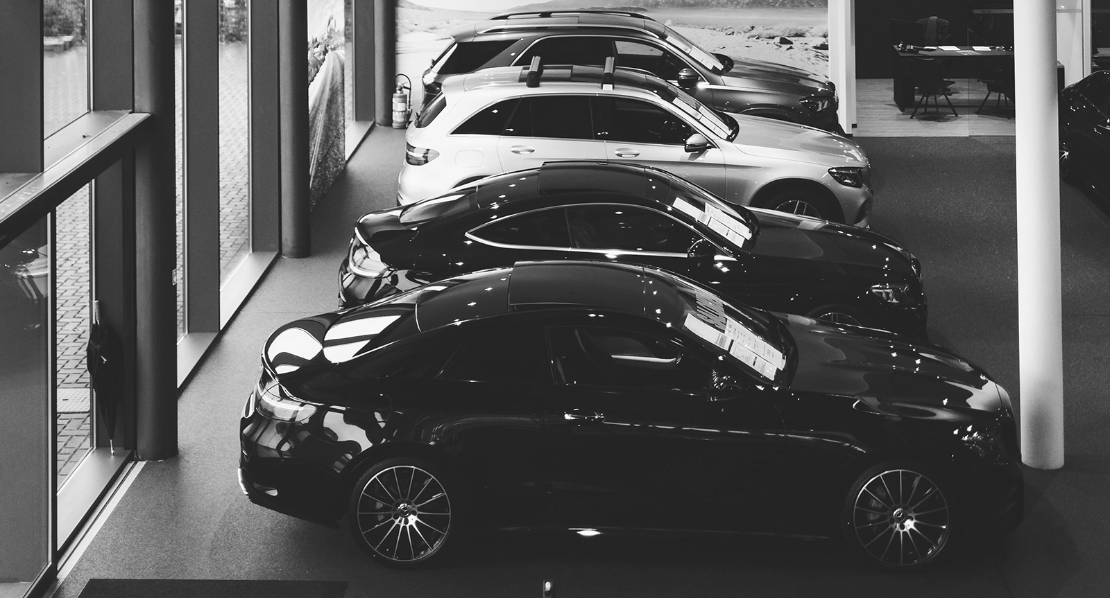 Ein Schwarz-Weiß-Foto von Autos, die in einem Ausstellungsraum geparkt sind.