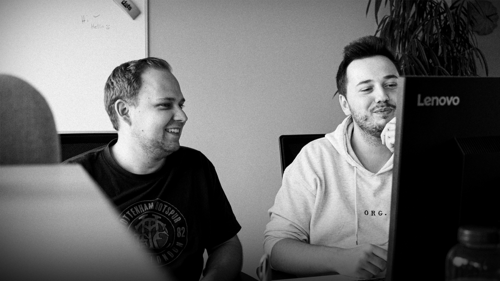 Ein Schwarz-Weiß-Foto von zwei BCxP-Mitarbeitern, die gemeinsam an einem Computer sitzten.