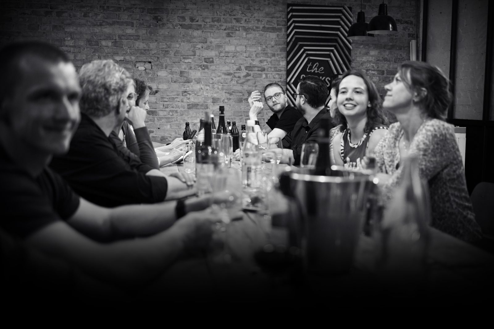 Ein Schwarz-Weiß-Foto einer Gruppe von Mitarbeiter:innen an einem Tisch, bei einem gemütlichen Teamabendessen gemeinsam.