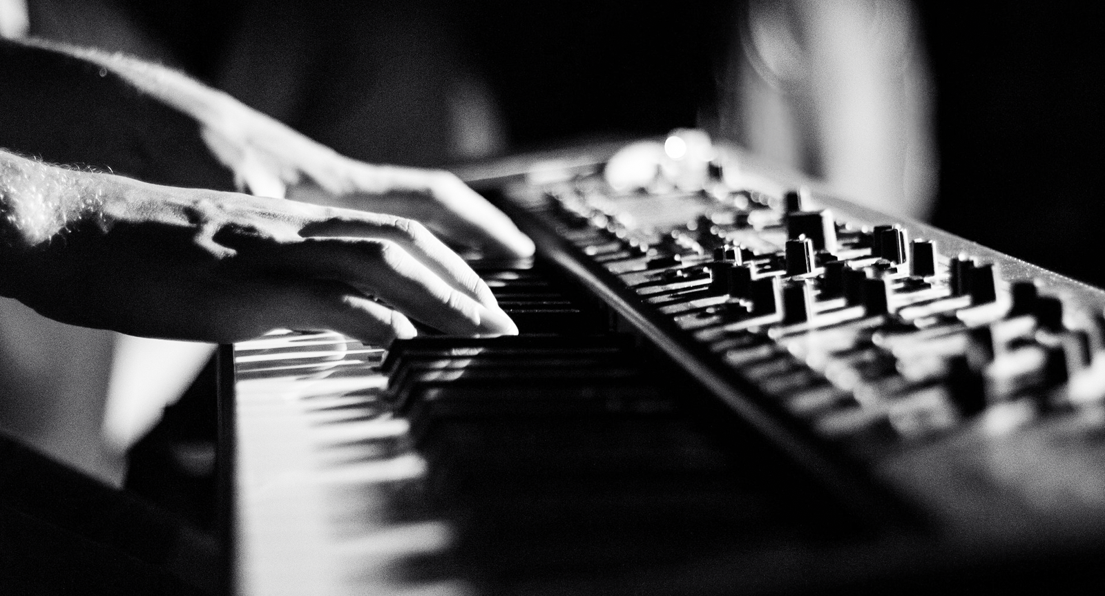 Ein Schwarz-Weiß-Foto einer Person, die auf einem Keyboard spielt.