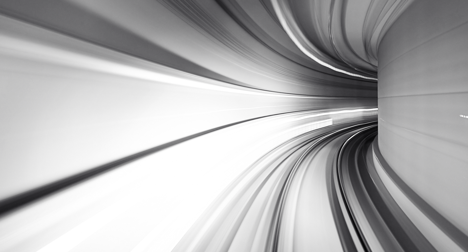 Ein Schwarz-Weiß-Bild eines Tunnels mit Lichteffekten die Schnelligkeit smybolisieren.