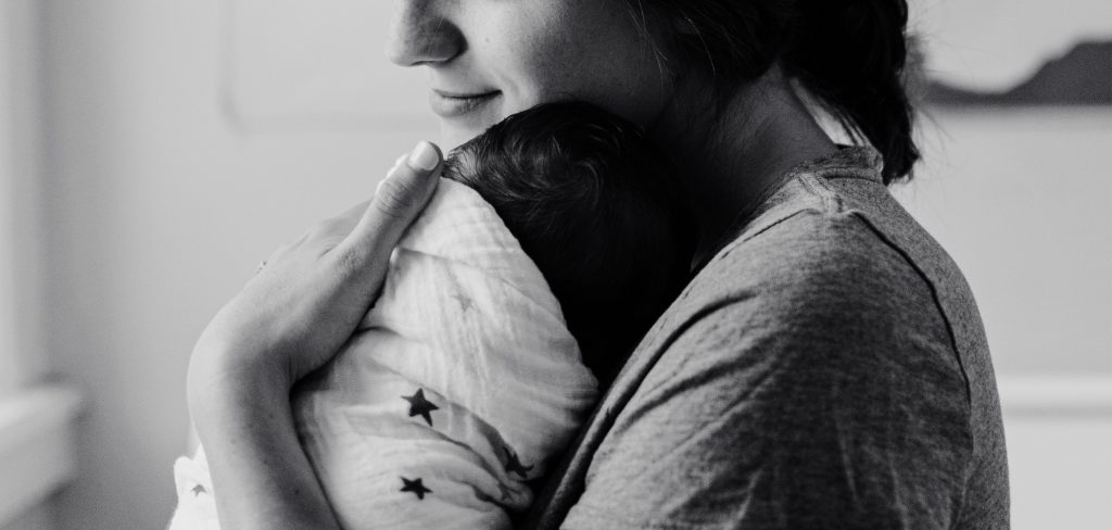 Schwarz-Weiß-Foto einer Frau die ein Baby im Arm hält.