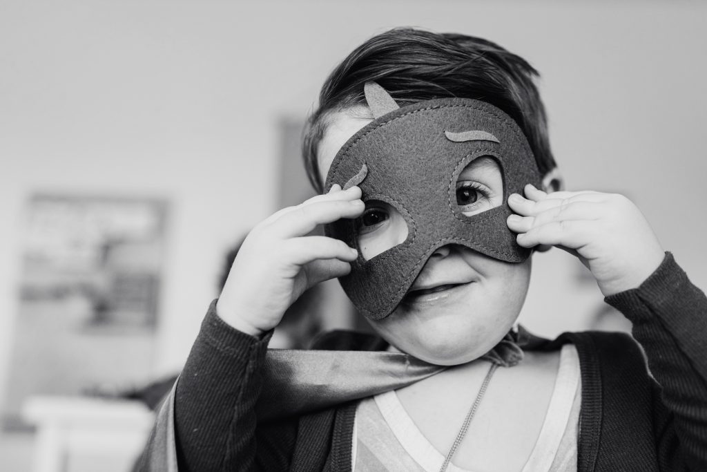 Schwarz-Weiß-Foto eines Jungen mit einer Maske im Gesicht.