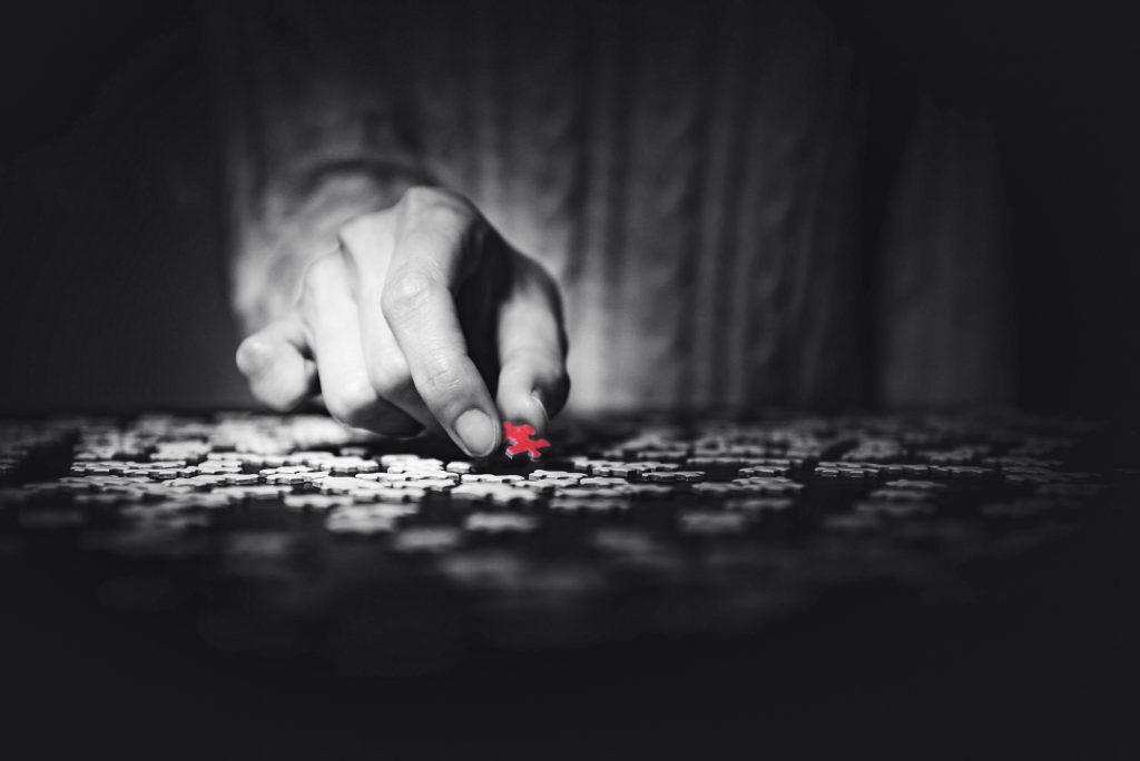 Die Hand einer Frau hält ein rotes Teil eines Puzzles.