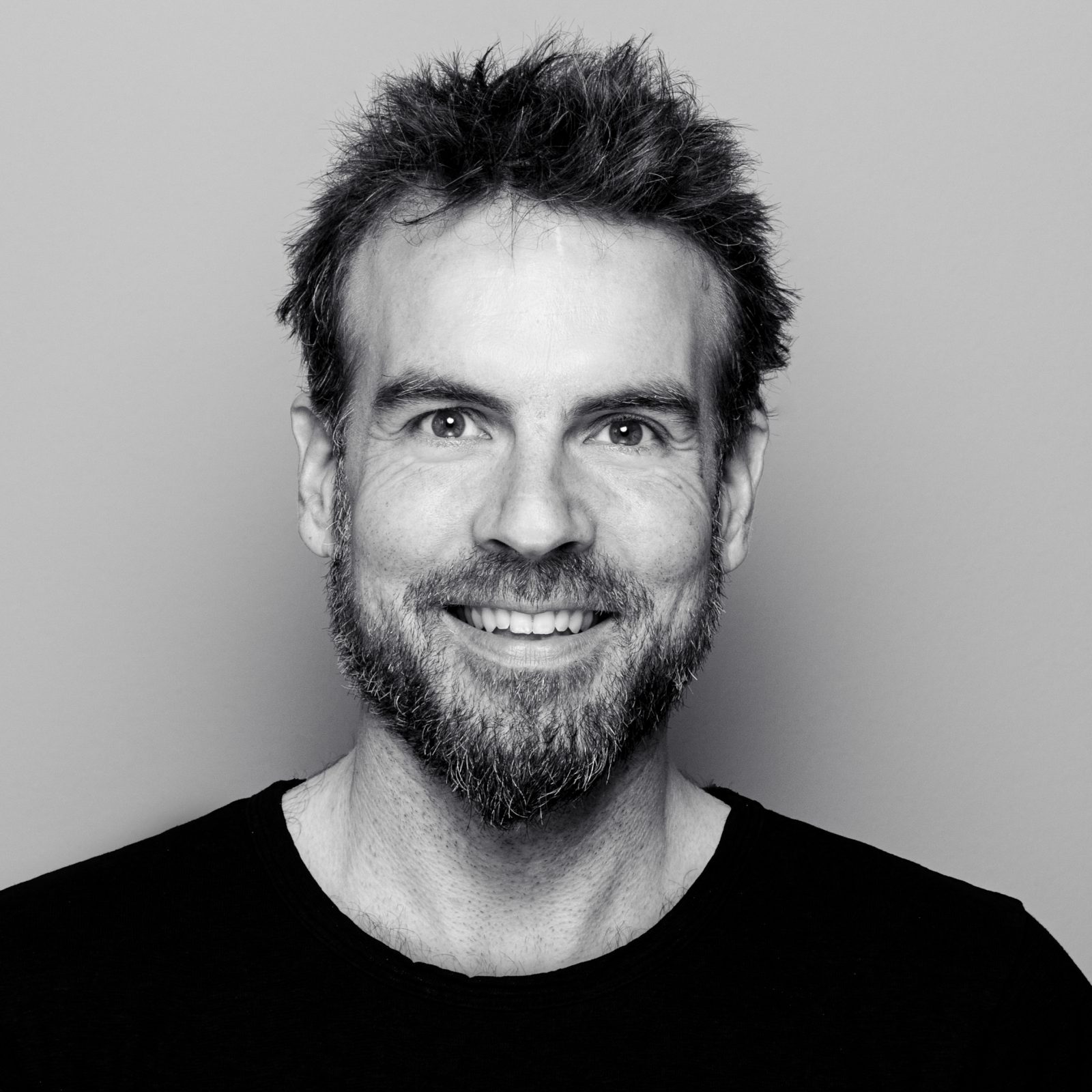 Ein Schwarz-Weiß-Foto eines lächelnden Mannes mit Bart.