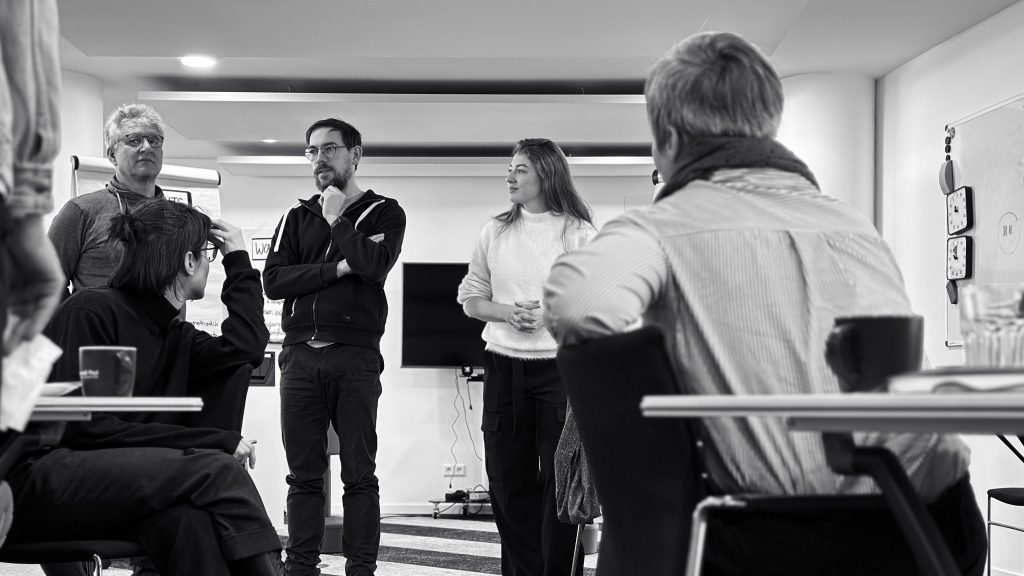 Ein Schwarz-Weiß-Bild einer Gruppe von BCxP-Mitarbeiter:innen, die miteinander diskutieren.