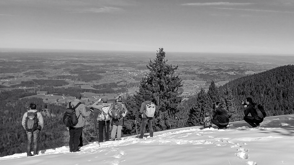 Eine Gruppe von Wanderern genießt die Aussicht von einem schneebedeckten Berggipfel.
