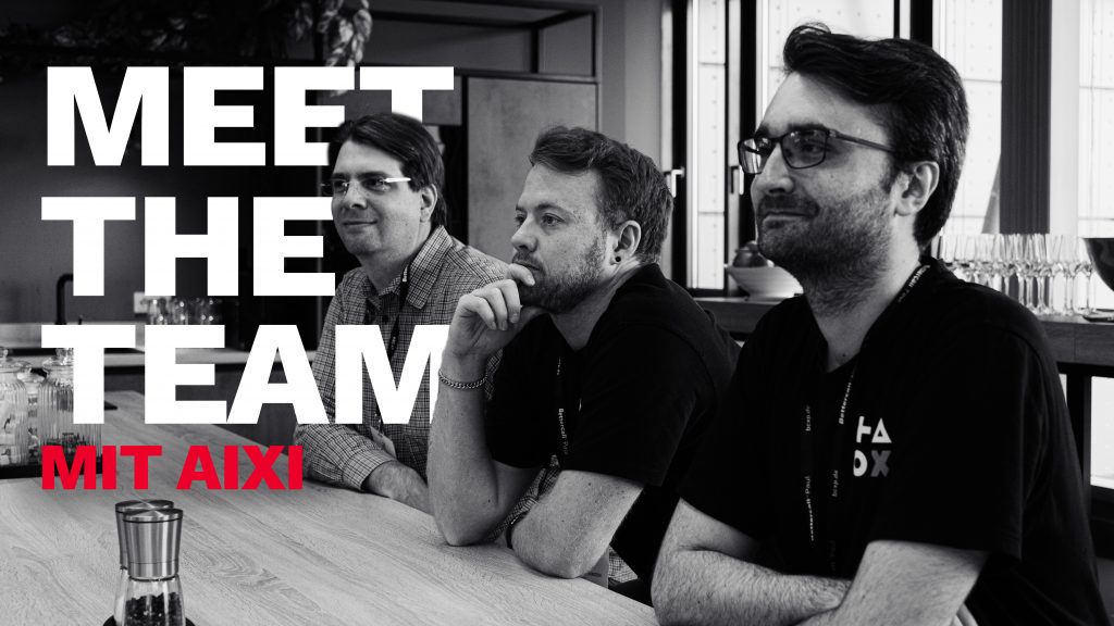 Drei Männer sitzen an einem Tisch in einer Büroumgebung; auf der linken Seite des Bildes ist in Fettdruck die Aufschrift „MEET THE TEAM MIT AIXI“ zu lesen.