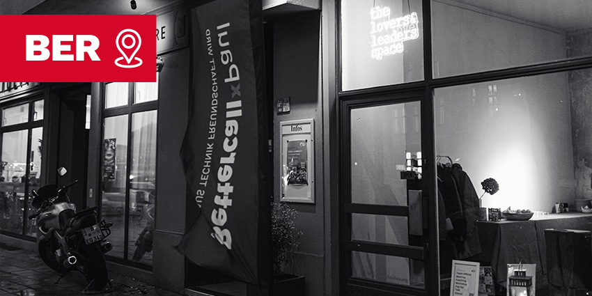 Ein Ladeneingang bei Nacht mit einem Banner mit der Aufschrift „bettercall x paul“ und einer Leuchtreklame im Fenster, auf der „the loverst leaders space“ steht.